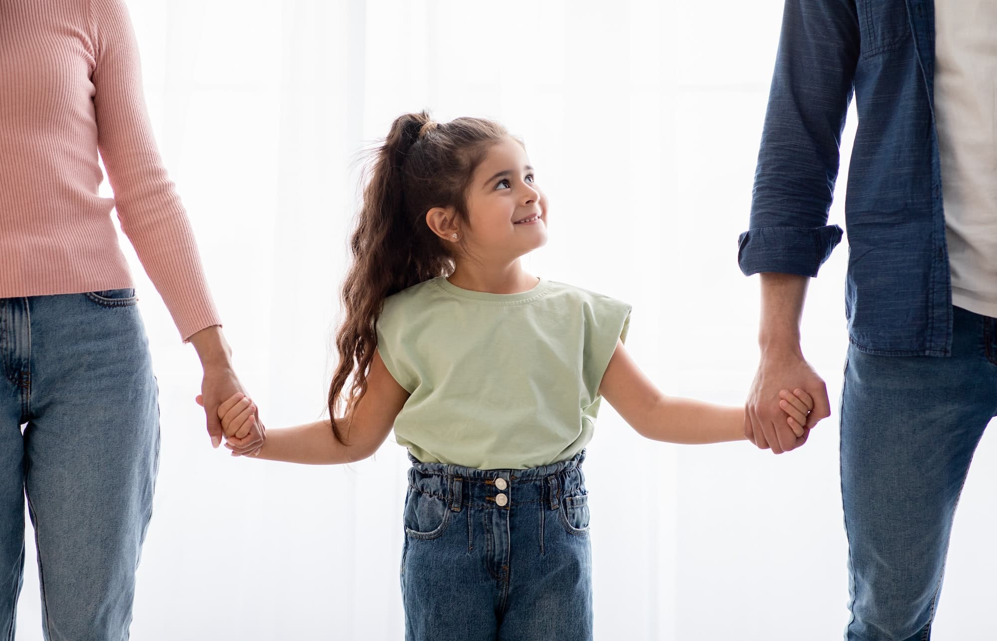 Adoption Concept. Adorable Little Girl Holding Hands With Unrecognizable Mom and&nbspDad